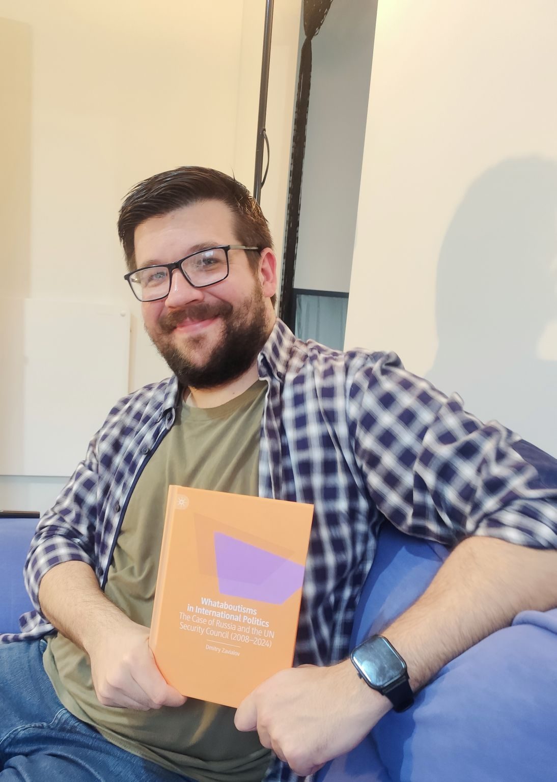 Dr Dmitry Zavialov holding a copy of Whataboutisms in International Politics